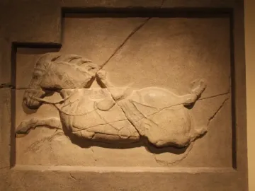 Stone relief of a horse from the Six Steeds of Zhao Mausoleum, shown in a rectangular frame with visible cracks across the weathered surface.