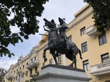 Francisco Pizarro equestrian statue mounted on a tall stone pedestal, with a floral wreath at its base.