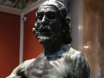 Bronze bust of Saint John the Baptist with long hair and a beard, showing a dark greenish patina.