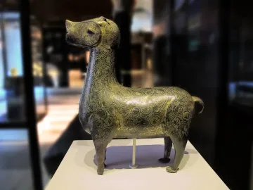 Stylized metallic deer sculpture from Madinat al Zahra on a white pedestal.