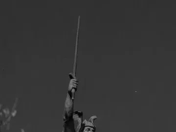 Close-up of the Hermann Monument statue showing a bearded warrior with a horned helmet, raised sword, and shield.
