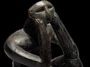 The Thinker of Cernavodă sculpture in a hunched seated pose with one hand supporting its head.
