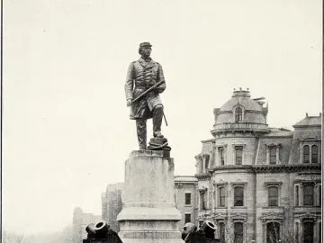 Admiral David G. Farragut statue atop a tall stone pedestal with naval decorations in a park setting.