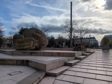 The sculpture Écoute shows a large stone head lying on its side with a cupped hand beside its face.