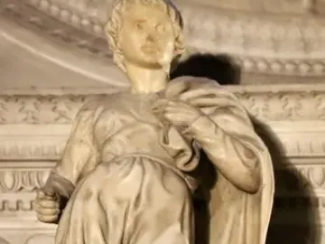 Marble statue of Saint Proculus standing in a short tunic and cloak among ornate stone carvings.