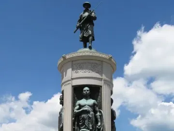 Victory Monument in Chicago with a bronze soldier statue atop a tall stone monument and figures in recessed niches below.