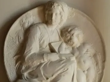 Pitti Tondo relief showing a seated woman holding a book with a child at her side and a smaller figure behind her shoulder.