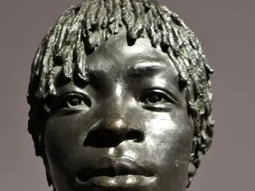 Woman of Central Africa bronze bust with short textured hair and layered beaded necklaces, shown in three-quarter profile.