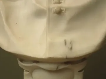 Lower portion of Cardinal Alessandro Peretti’s white marble bust, showing draped folds and a decorated pedestal base.