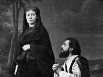 A woman in a dark flowing gown and veil stands beside a kneeling bearded man with clasped hands in The Stone Guest.