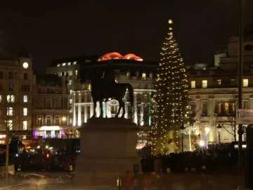 Equestrian Statue of George IV on a pedestal at night, with a lit Christmas tree in the background.
