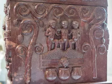 Detail of the Sarcophagus of Constantina showing winged child-like figures, vine scrolls with grape clusters, and jars below.