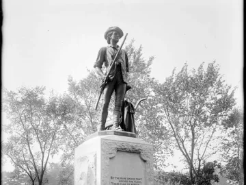 The Minute Man statue shows a man in colonial attire holding a musket beside a plow handle on a stone pedestal.