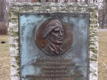 Monument to the Battle of Monte Cassino with a bronze plaque and bas-relief portrait set into rough stone blocks.