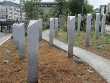 Pink Triangle Park with tall granite pillars arranged in a triangular formation along a sloped gravel path.