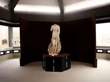 Venus Landolina marble statue standing on a dark pedestal in a museum gallery.