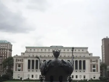 Alma Mater, a bronze seated female figure holding an open book and scepter on a stone pedestal outside Columbia University.