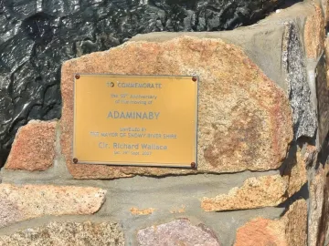 Golden commemorative plaque on the Big Trout, set in a rough stone wall