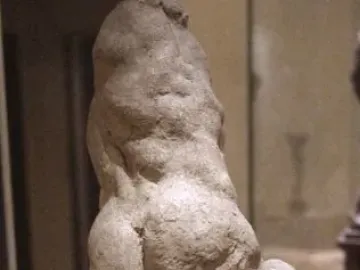 Two Wrestlers in rough light-colored clay on a dark base in a gallery setting.