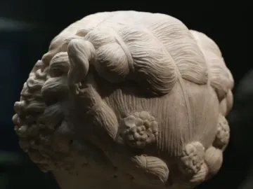 Bust of a Young Woman showing the back and side of the sculpted head with an elaborate wavy hairstyle and carved rosette motifs.