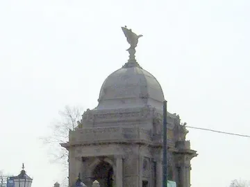 Hurlbut Memorial Gate with a domed stone structure, arched openings, and columns behind a wire fence