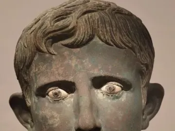 Bronze Meroë Head with greenish-brown patina, wavy hair, and inlaid eyes