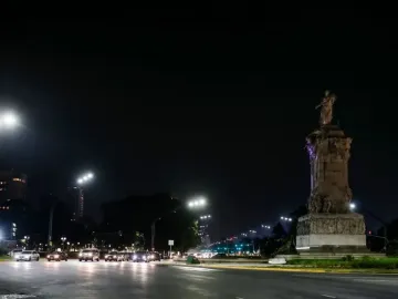 The Monument to the Carta Magna and Four Regions of Argentina lit in purple at night beside a busy city road.