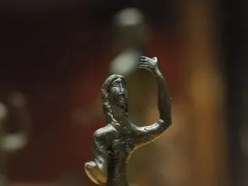 Neuvy-en-Sullias Hoard bronze statuette of a slender figure with one arm raised on a marbled base.