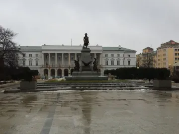 Tadeusz Kościuszko Monument on a stone pedestal in front of a white columned building in Warsaw.