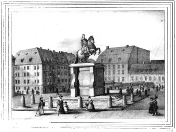The Golden Rider equestrian statue on a carved pedestal in a town square, surrounded by a metal fence.
