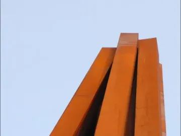 Neuf Lignes Obliques sculpture with tall rusty orange metal beams rising at sharp angles against a pale sky.