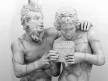 Pan and Daphne marble sculpture showing a bearded, horned figure embracing a nude youth holding a small musical instrument.