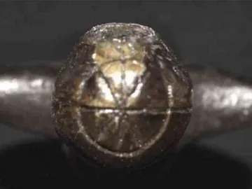 Close-up of the Venus of Langenzersdorf showing a dark, textured surface with geometric patterns.