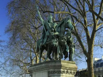 Charlemagne and His Leudes equestrian statue on a tall stone pedestal in a park, with two standing figures beside the horse.
