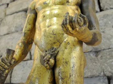 Gilded torso of Hercules of the Forum Boarium holding a club and small round objects.