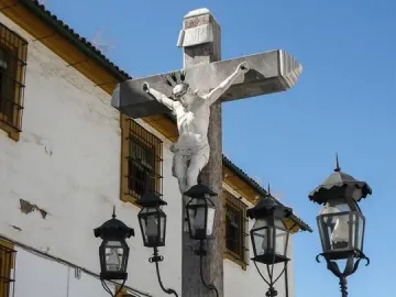 Christ of the Lanterns stone crucifix with a white statue of Christ and wrought-iron lanterns