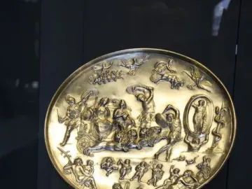 The Parabiago Plate, a circular gold-toned relief plate with mythological figures and animals, displayed on a stand.