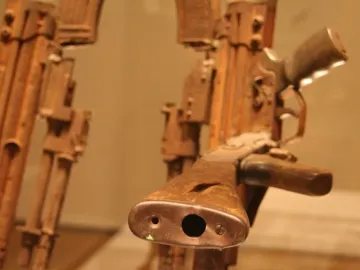 Close-up of the Throne of Weapons made from heavily corroded firearms, with one gun’s muzzle and wooden stock prominent in the foreground.