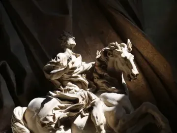 The Vision of Constantine, a white marble equestrian statue lit by sunlight inside an ornate niche.