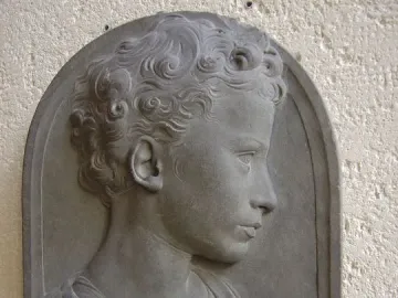 Bust of a child shown in profile, with tightly curled hair and draped clothing.