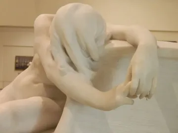 Desolation, a white marble sculpture of a bowed figure with an outstretched hand resting on a textured block.