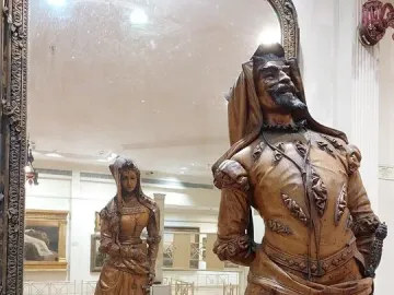 Mephistopheles and Margaretta wooden sculpture with a bearded man in elaborate attire and a mirrored reflection of a woman in a long gown