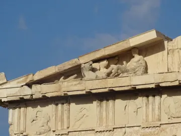 Weathered marble sculptures in the Parthenon pediment above carved panels on the Acropolis, Athens.