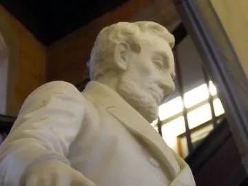 Close-up of the Emancipation Memorial showing Abraham Lincoln’s bearded marble figure looking downward with a rolled document in hand.