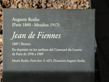 Information plaque for Jean de Fiennes by Auguste Rodin with white text on a dark gray surface.