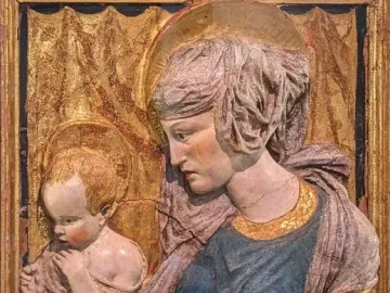 Painted terracotta Madonna and Child relief with halos and worn, cracked surfaces.