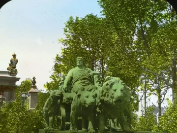 Marc Anton Group sculpture showing a robed man seated in a chariot drawn by lions on a pedestal among trees.