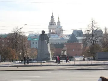 Monument to Karl Marx in a Moscow plaza, with a large stone statue on a rough base near trees and surrounding buildings.
