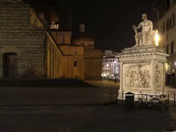 Giovanni delle Bande Nere statue lit at night, seated in armor on an ornate pedestal.