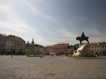 Matthias Corvinus Monument bronze equestrian statue on a white stone pedestal in a cobblestone square with historic buildings and pedestrians